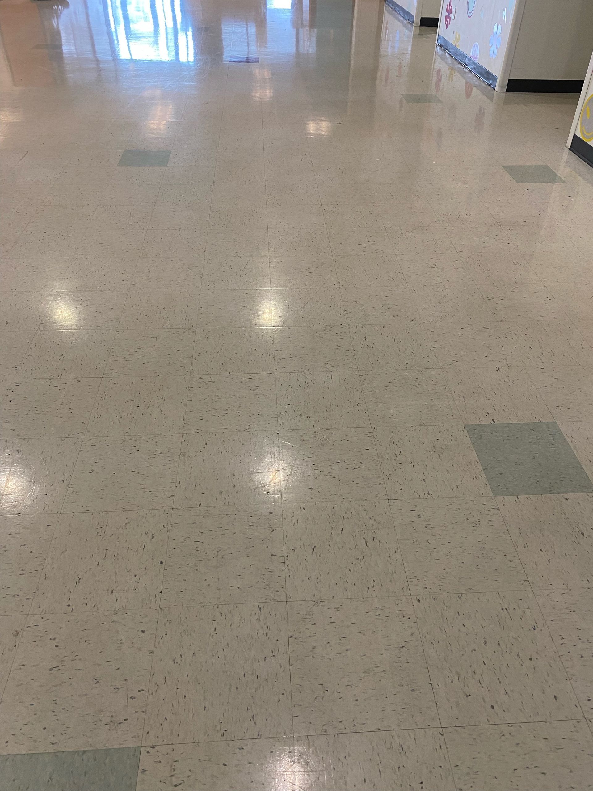 Empty speckled school hallway with glossy tiled floor and bright overhead lights