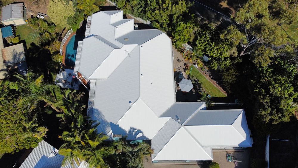 An aerial view of a house with a white roof after being painted.