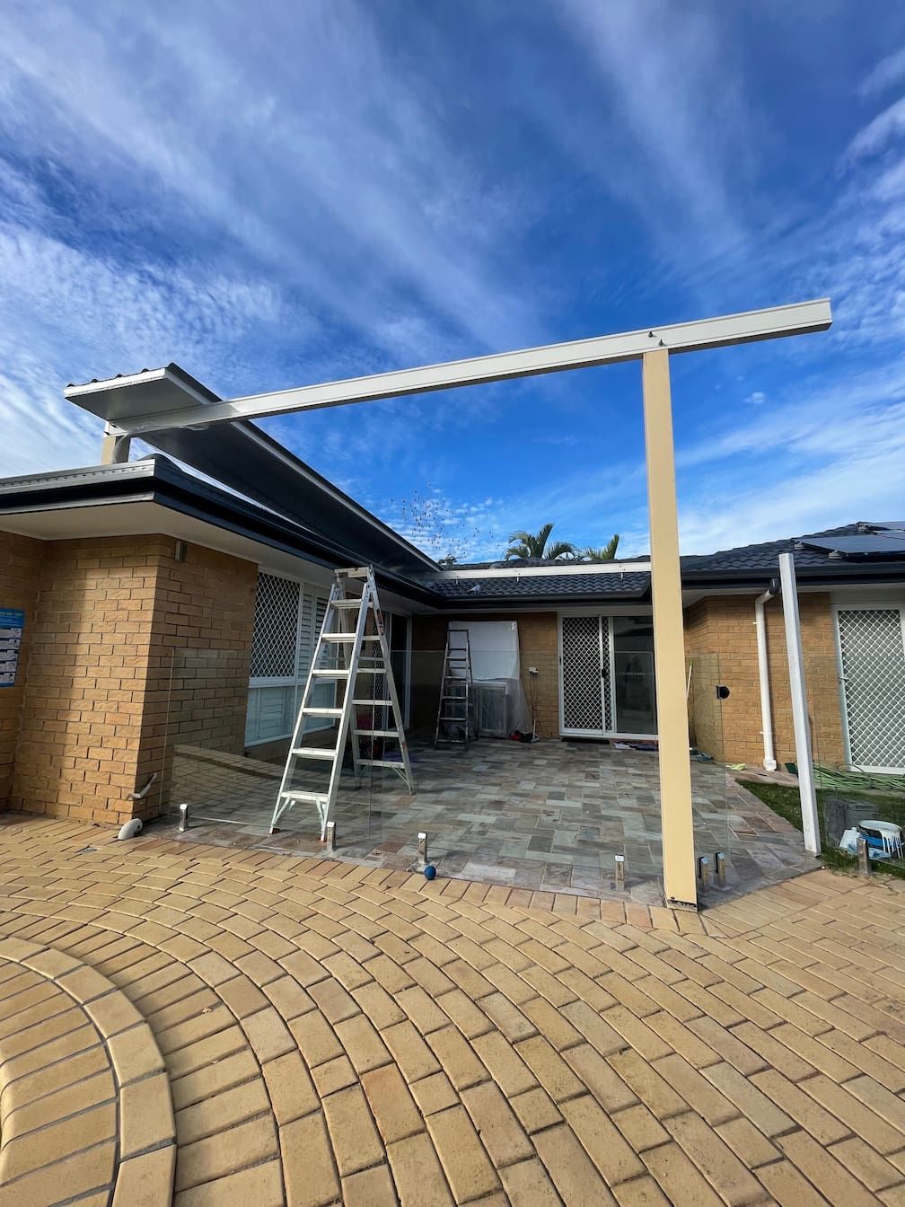 A ladder is sitting in front of a house where a patio is being built.