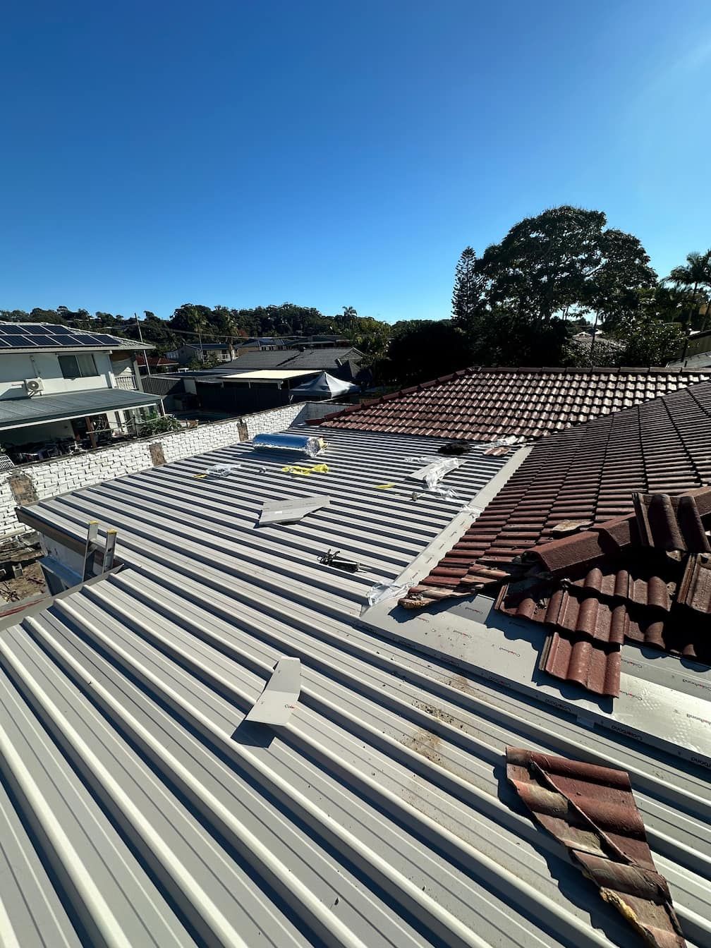 A Gold Coast roof with a lot of tiles on it and a blue sky in the background.