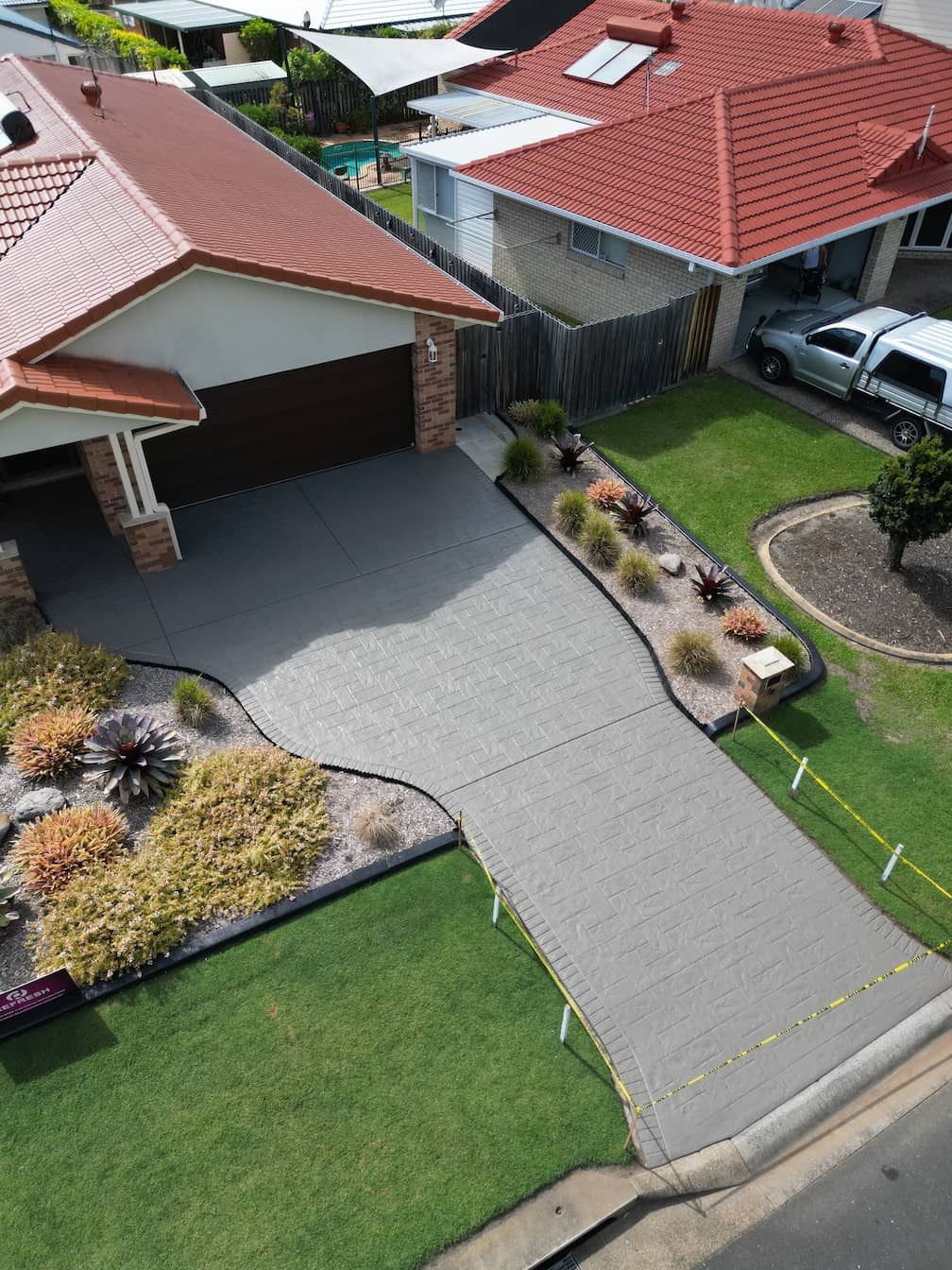 An aerial view of a house with a driveway and a red roof.