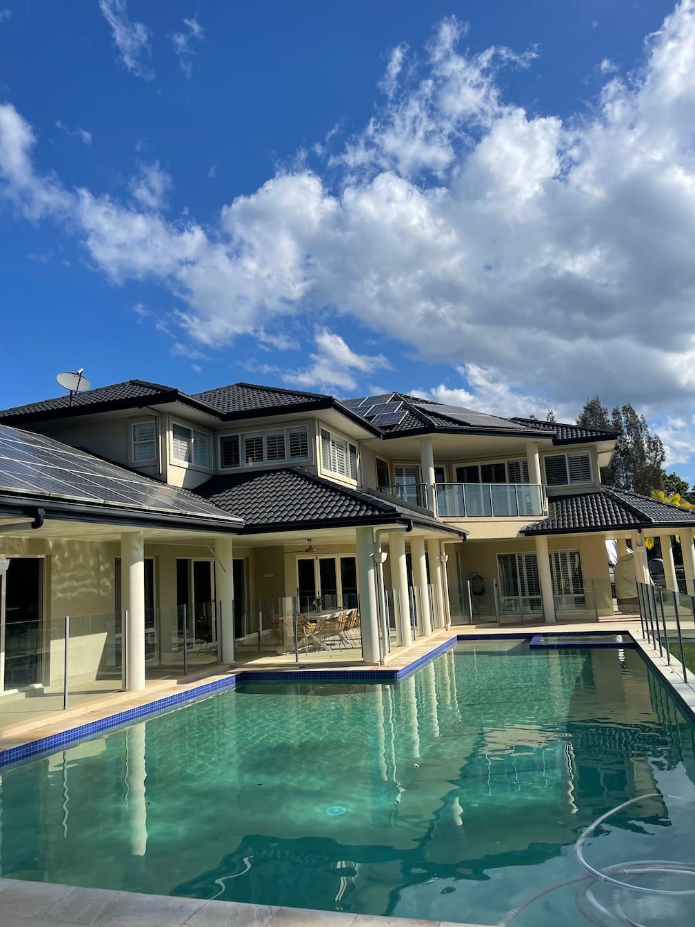A large house with a large roof and swimming pool in front of it.