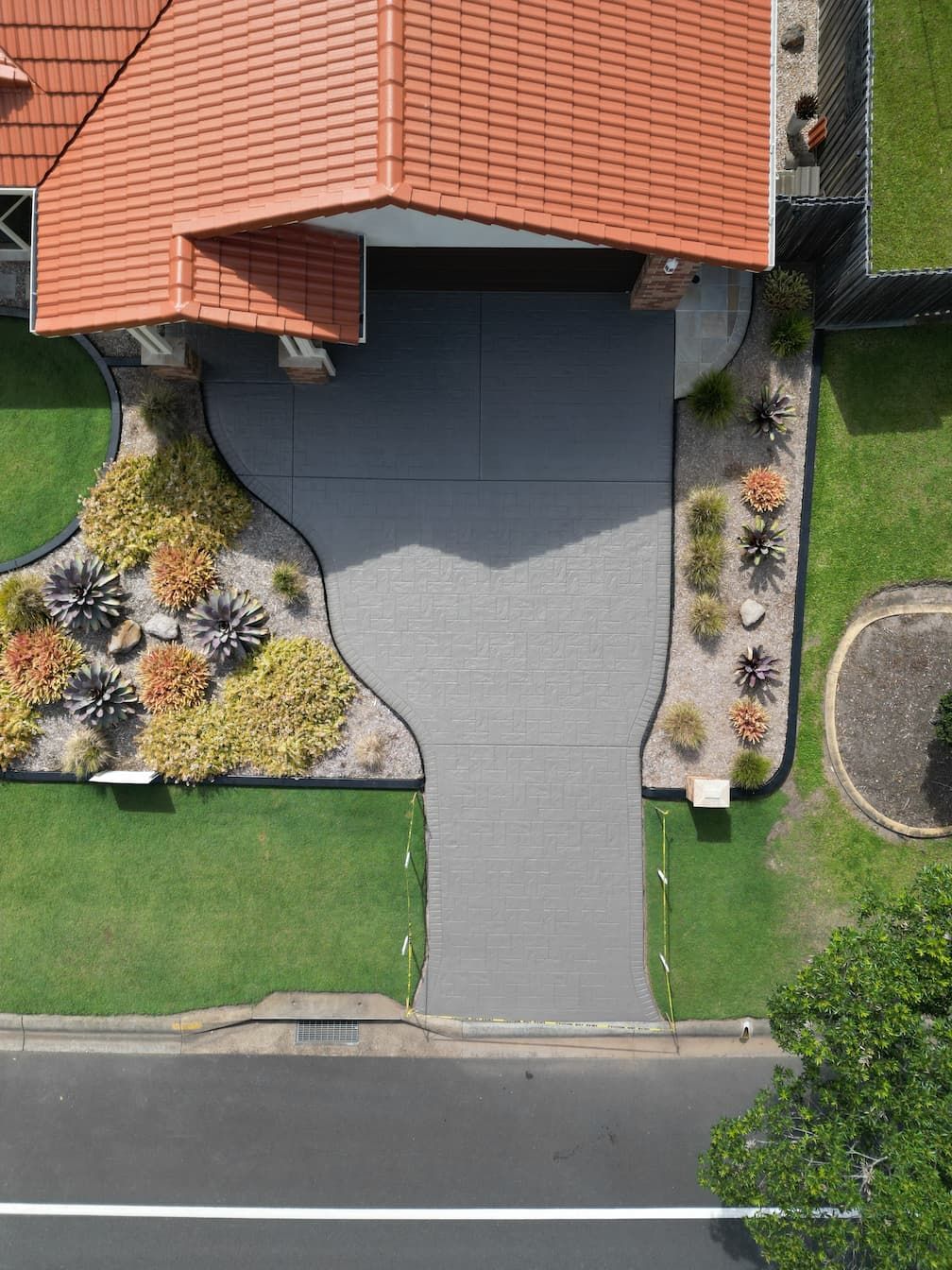 An aerial view of a house with a driveway and a red tile roof