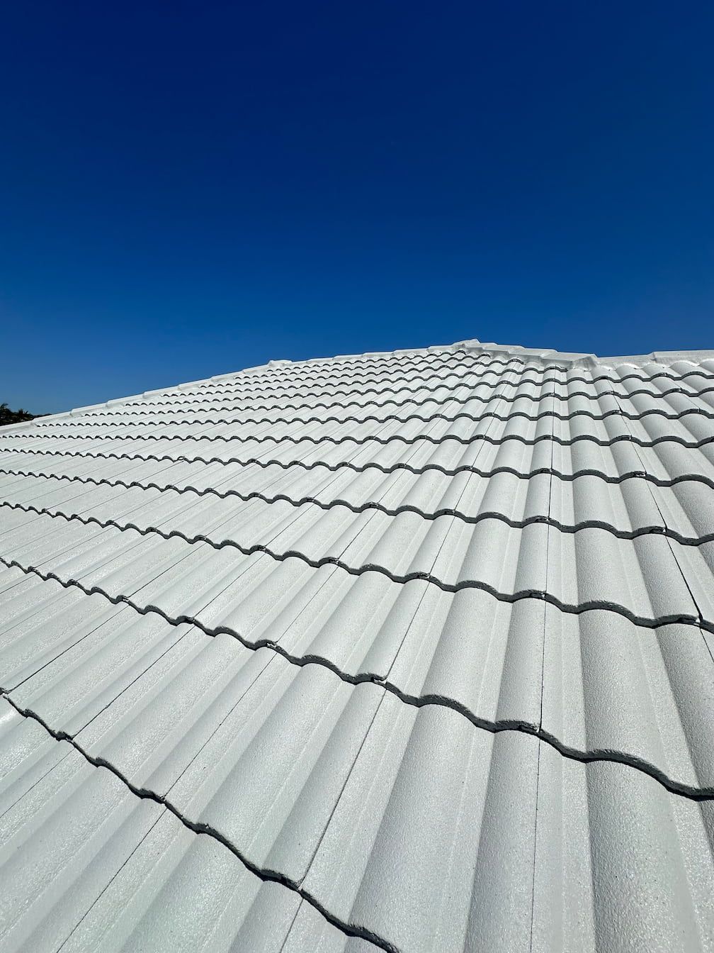 A painted white tiled roof with a blue sky in the background.