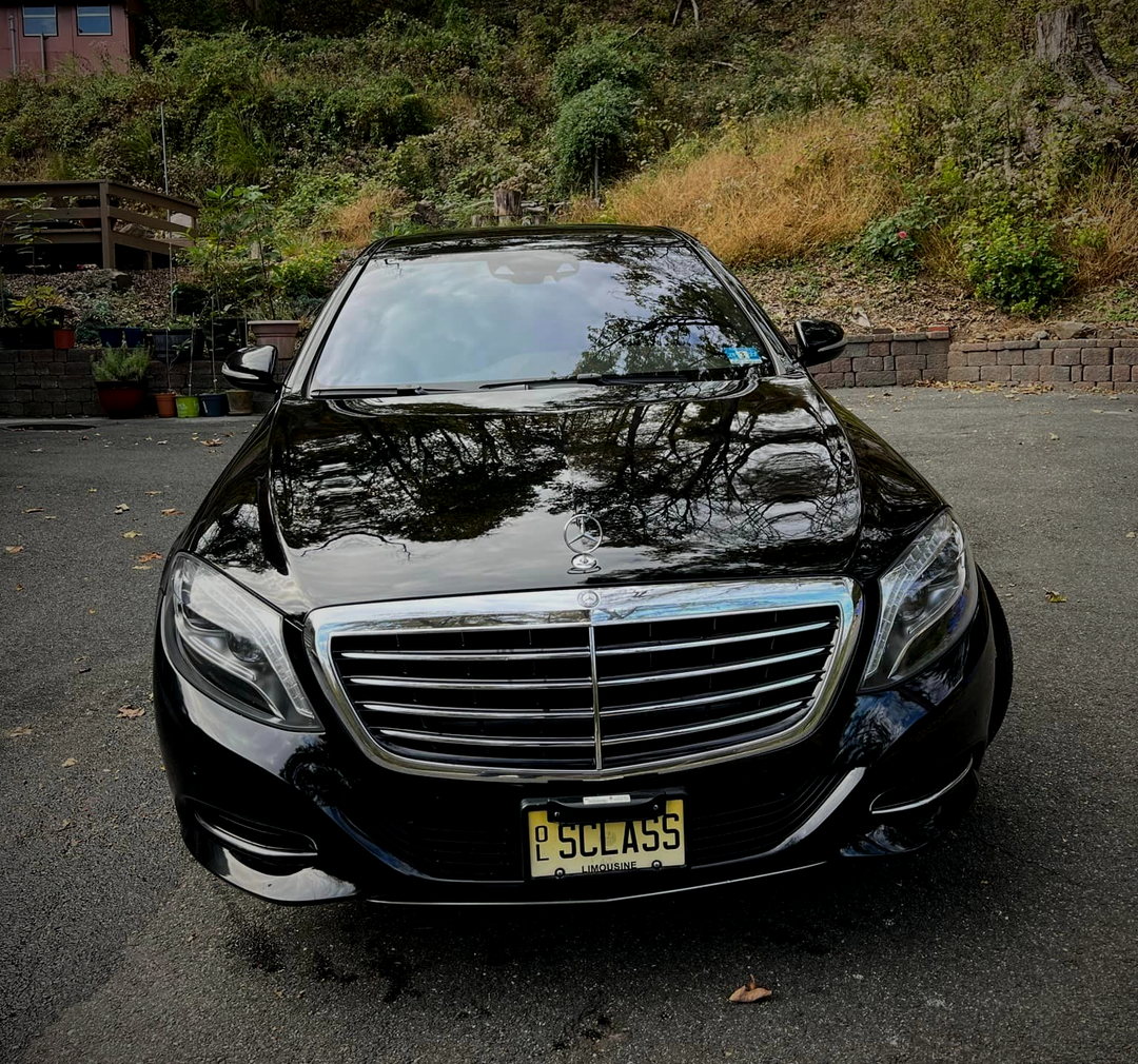 A black mercedes benz is parked in a parking lot