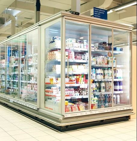 Vetrina refrigerata in un supermercato, piena di vari prodotti alimentari e bevande.