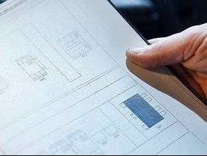 Mano che tiene in mano un documento con uno schema elettrico.