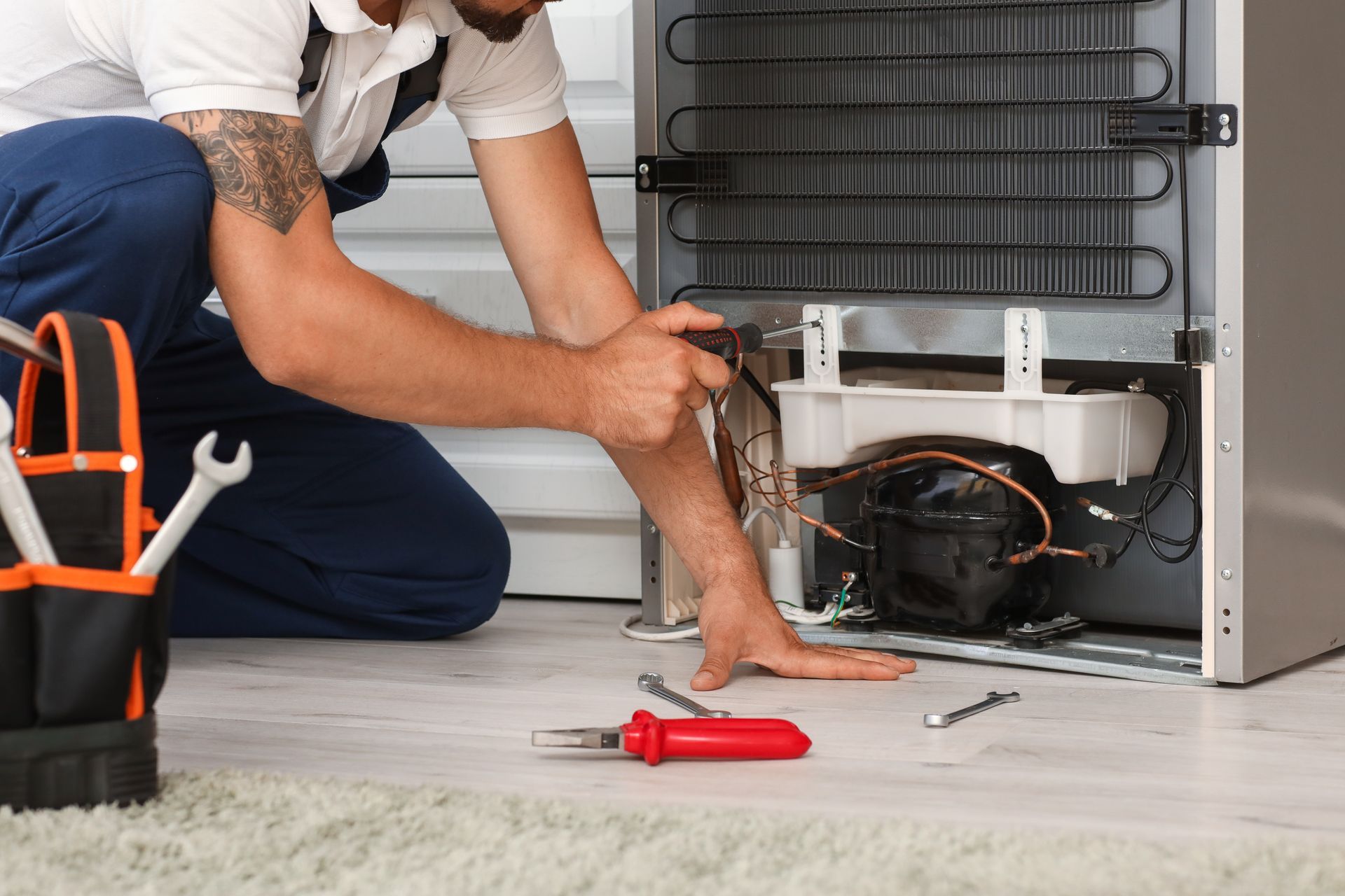 Worker repairing a fridge in the kitchen.