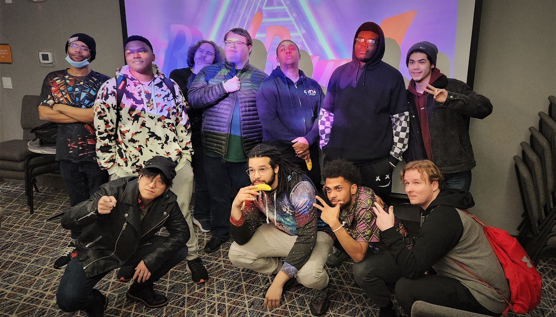 Group of people posing in a room, in front of a colorful projected background. 