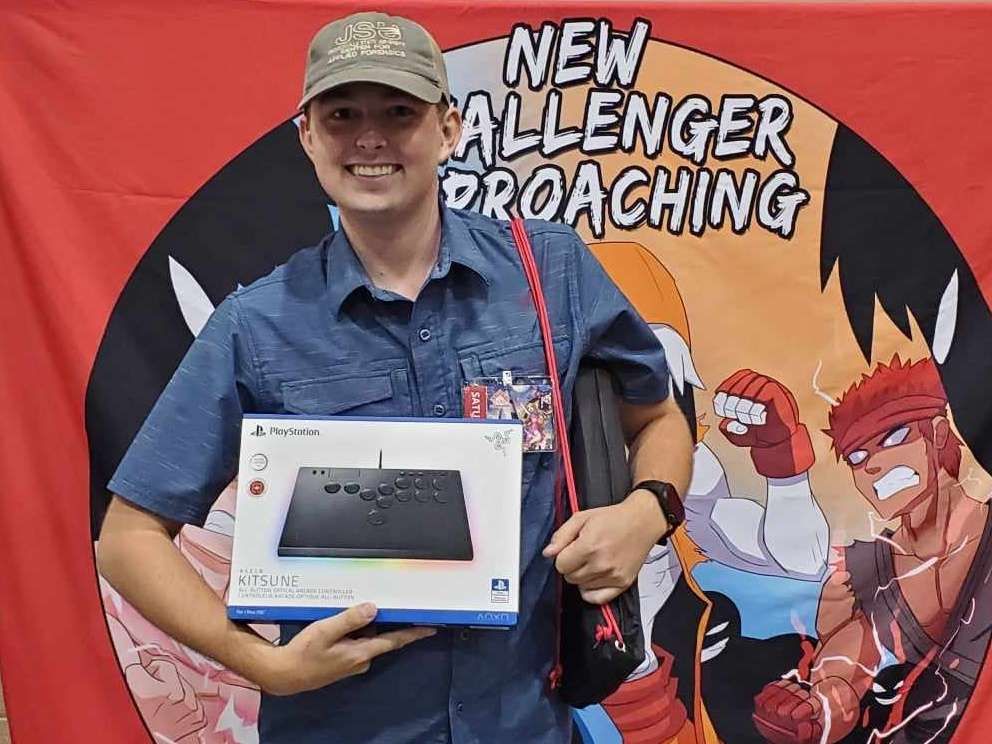 A person holding a gaming controller box at a convention booth with a 