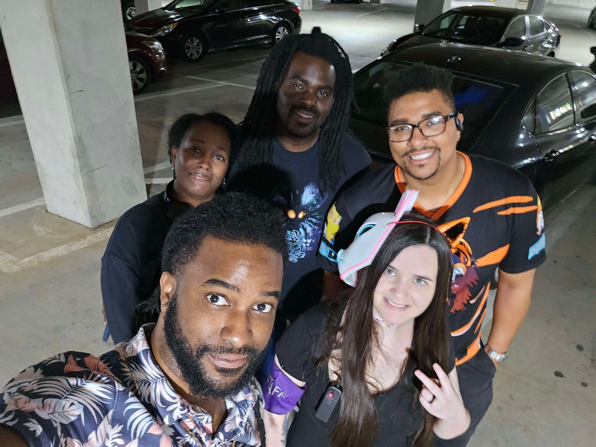 Group of five people smiling and looking at the camera in a parking garage.