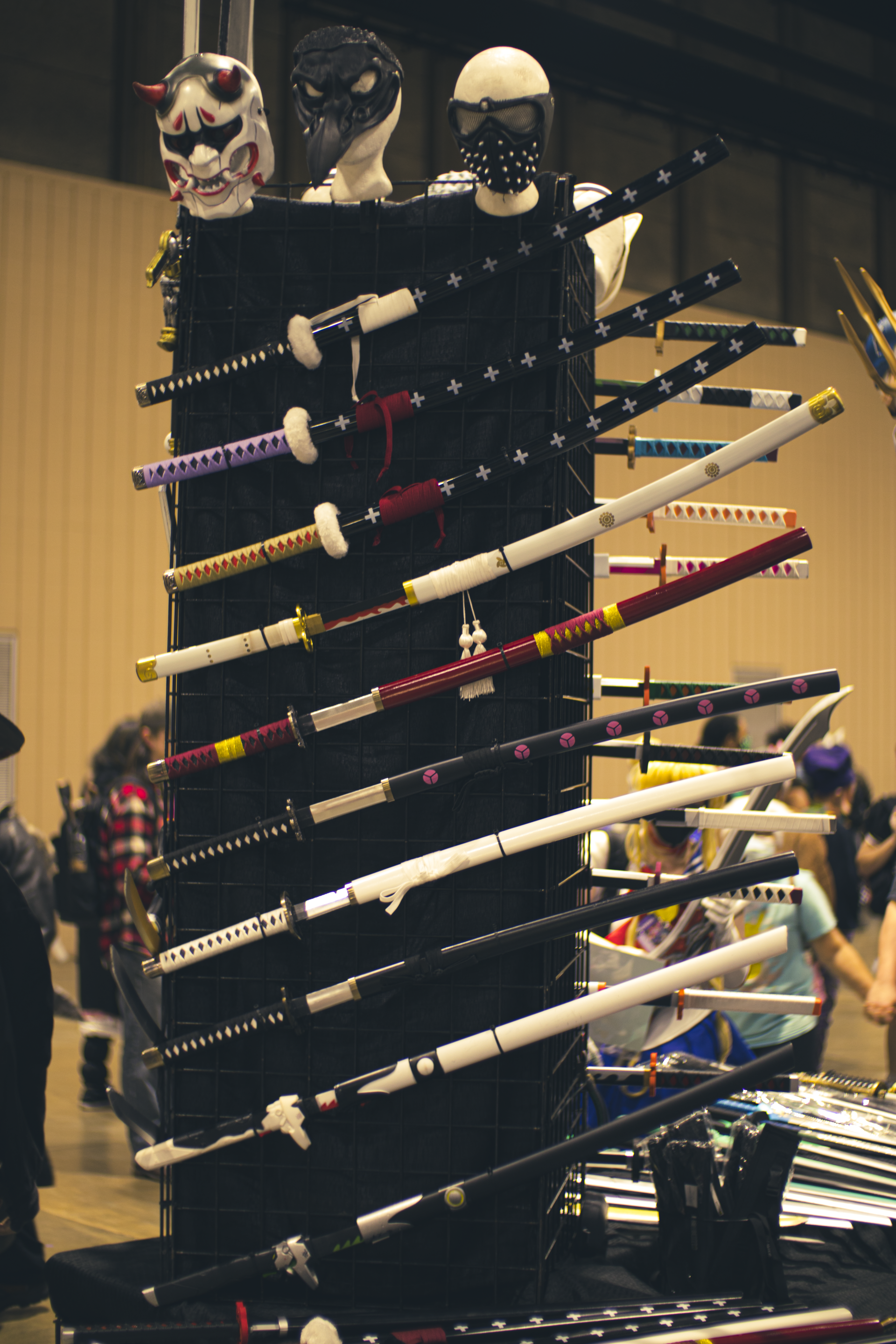 Display of decorative swords at a convention, with masks on top.