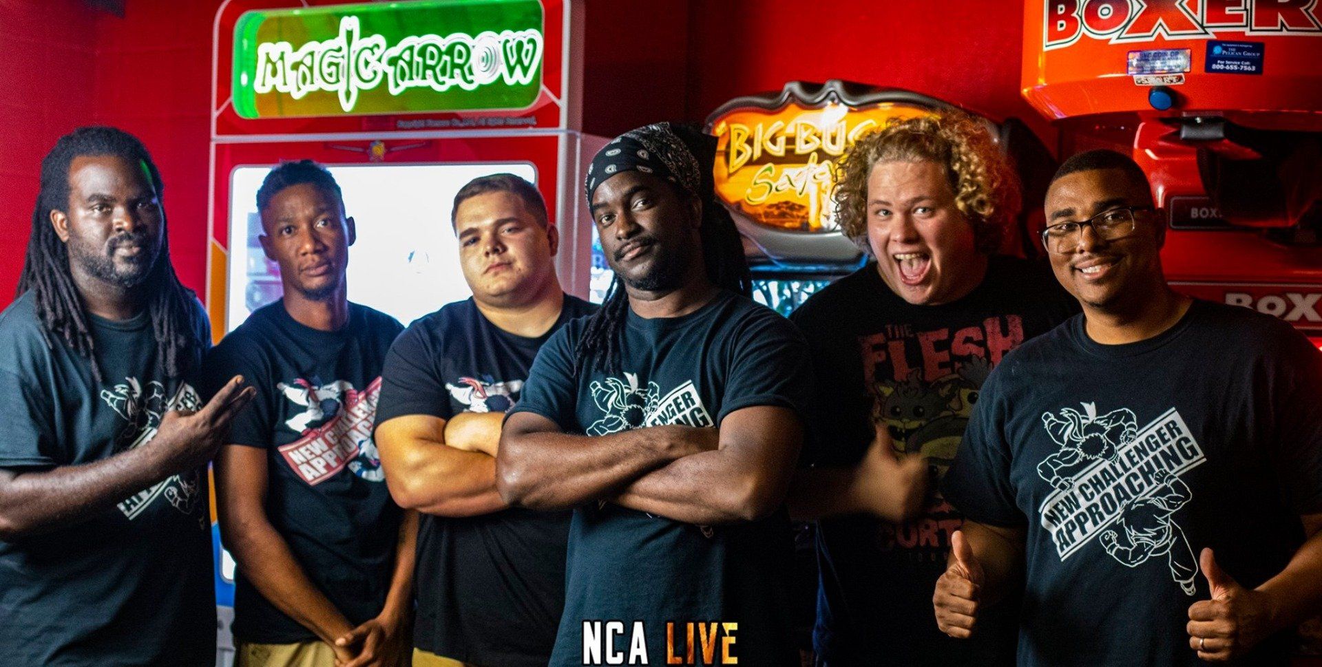 Group of six people standing in front of arcade games, smiling and posing.
