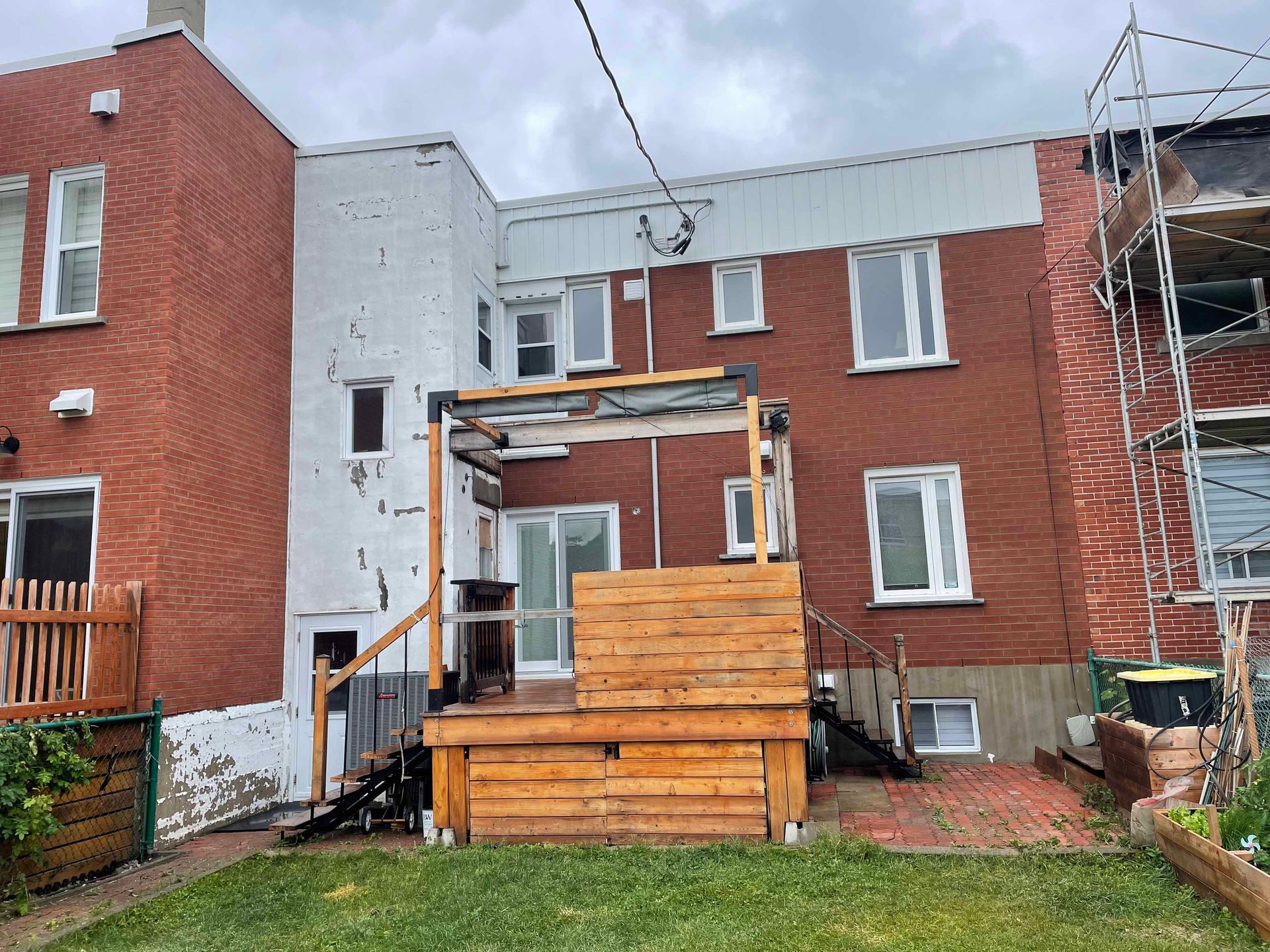 Vue arrière d'un bâtiment en briques avec une terrasse en bois et un petit jardin.