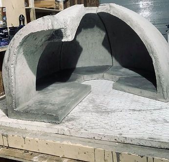 Vue en coupe d'un dôme de four à pizza en béton, à l'intérieur. Structure grise sur une base en béton.
