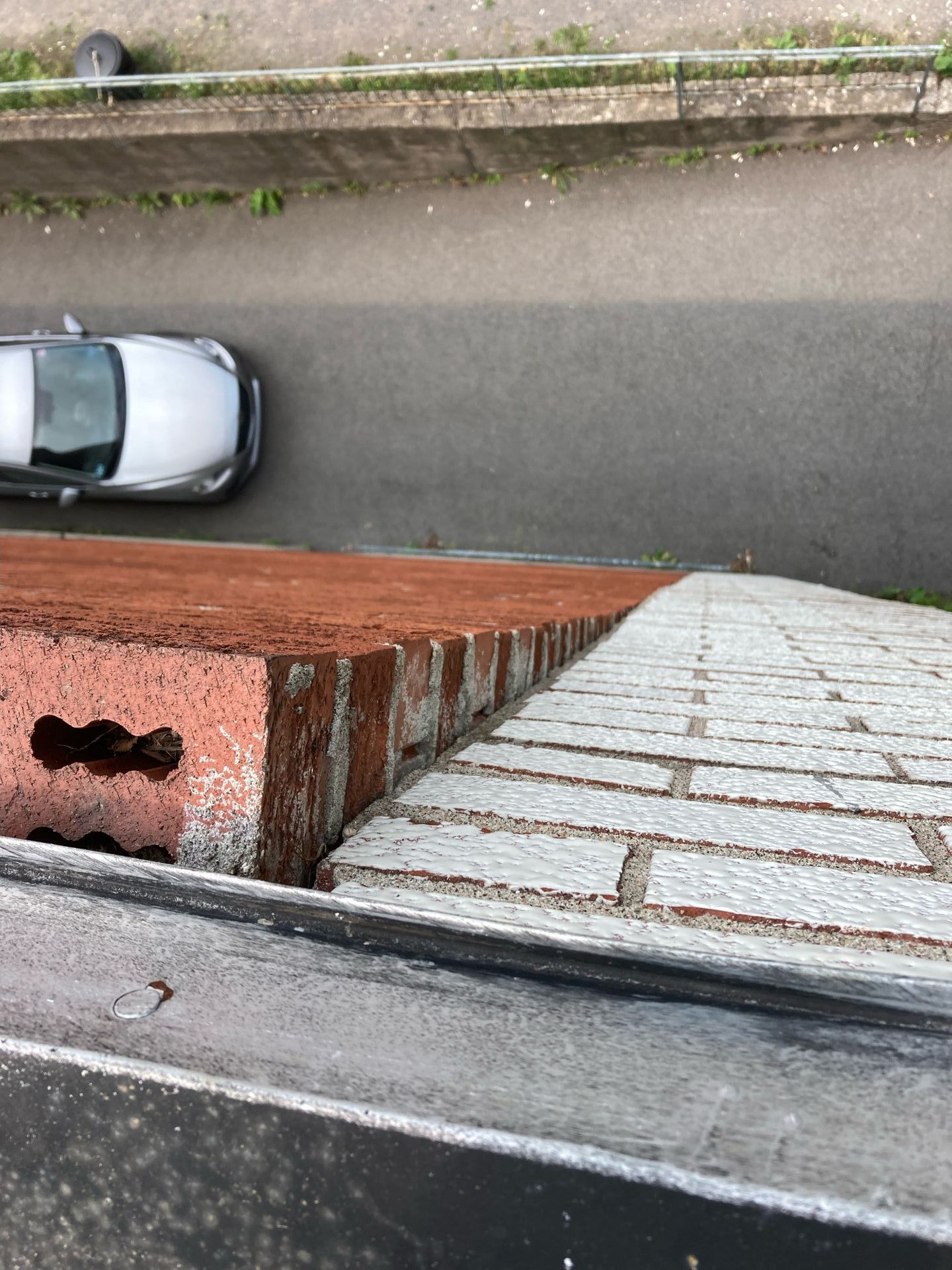 Vue aérienne d'un mur de briques, avec une voiture garée dans la rue en contrebas.