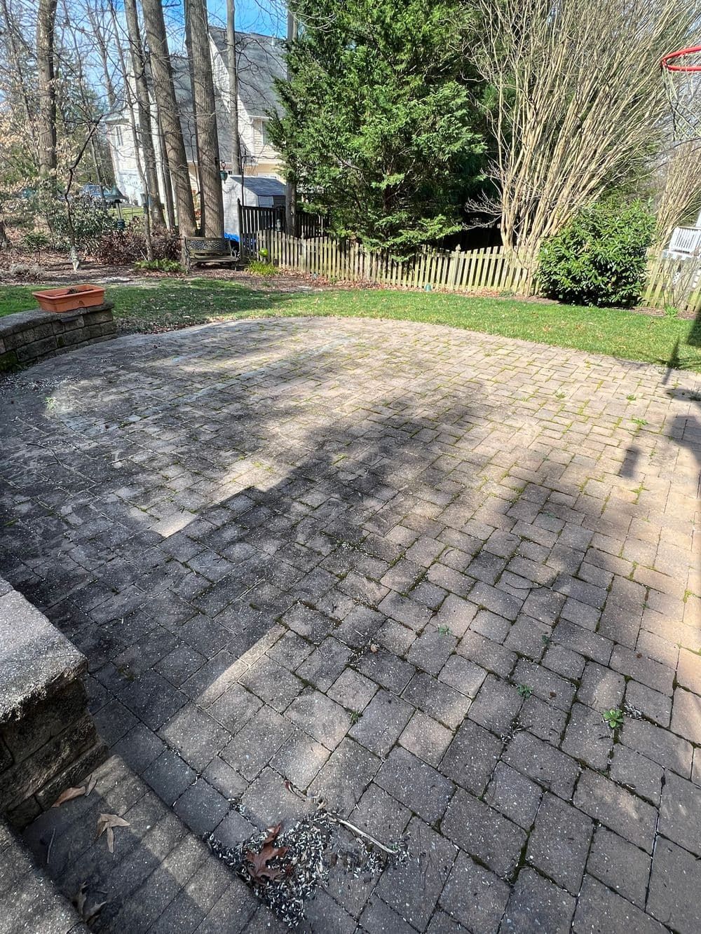 Brick patio with steps leading to a yard with grass and trees.