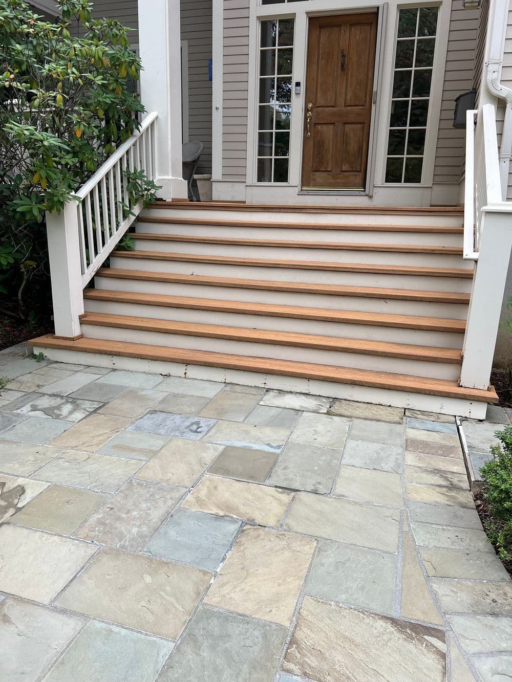 Stone walkway leading to wooden porch stairs and a front door.
