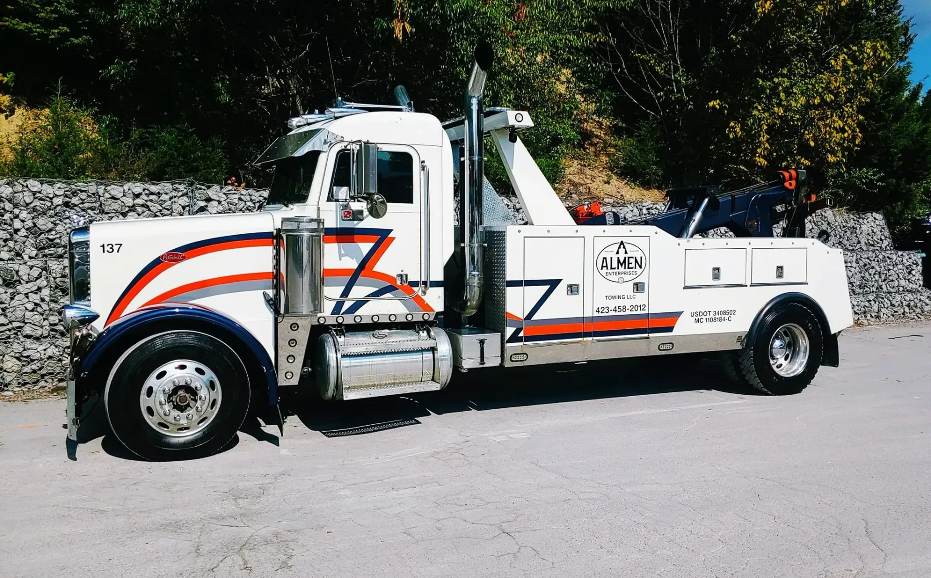 A white tow truck is parked in a gravel lot