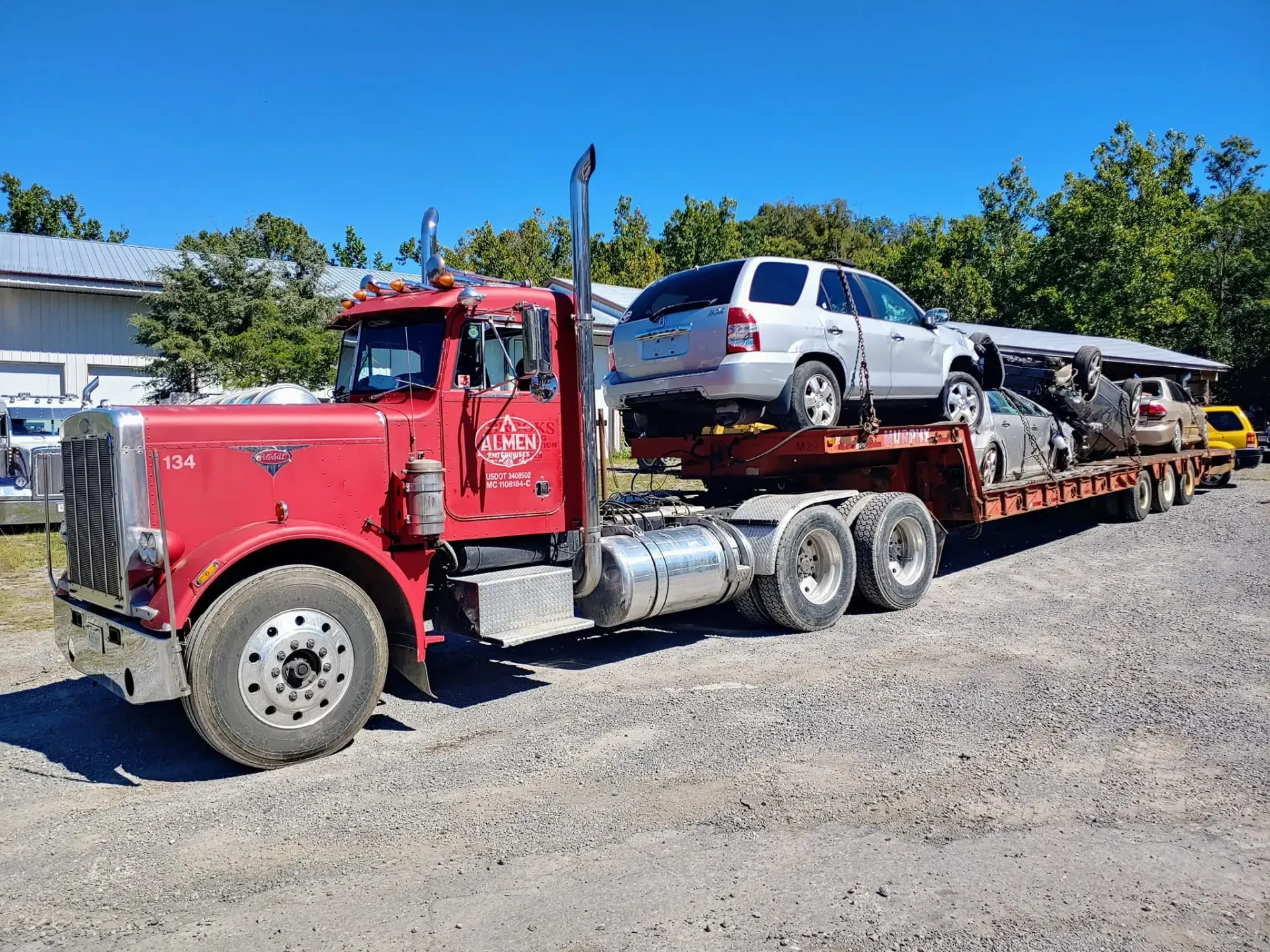 A red semi truck is carrying a bunch of cars on a trailer.