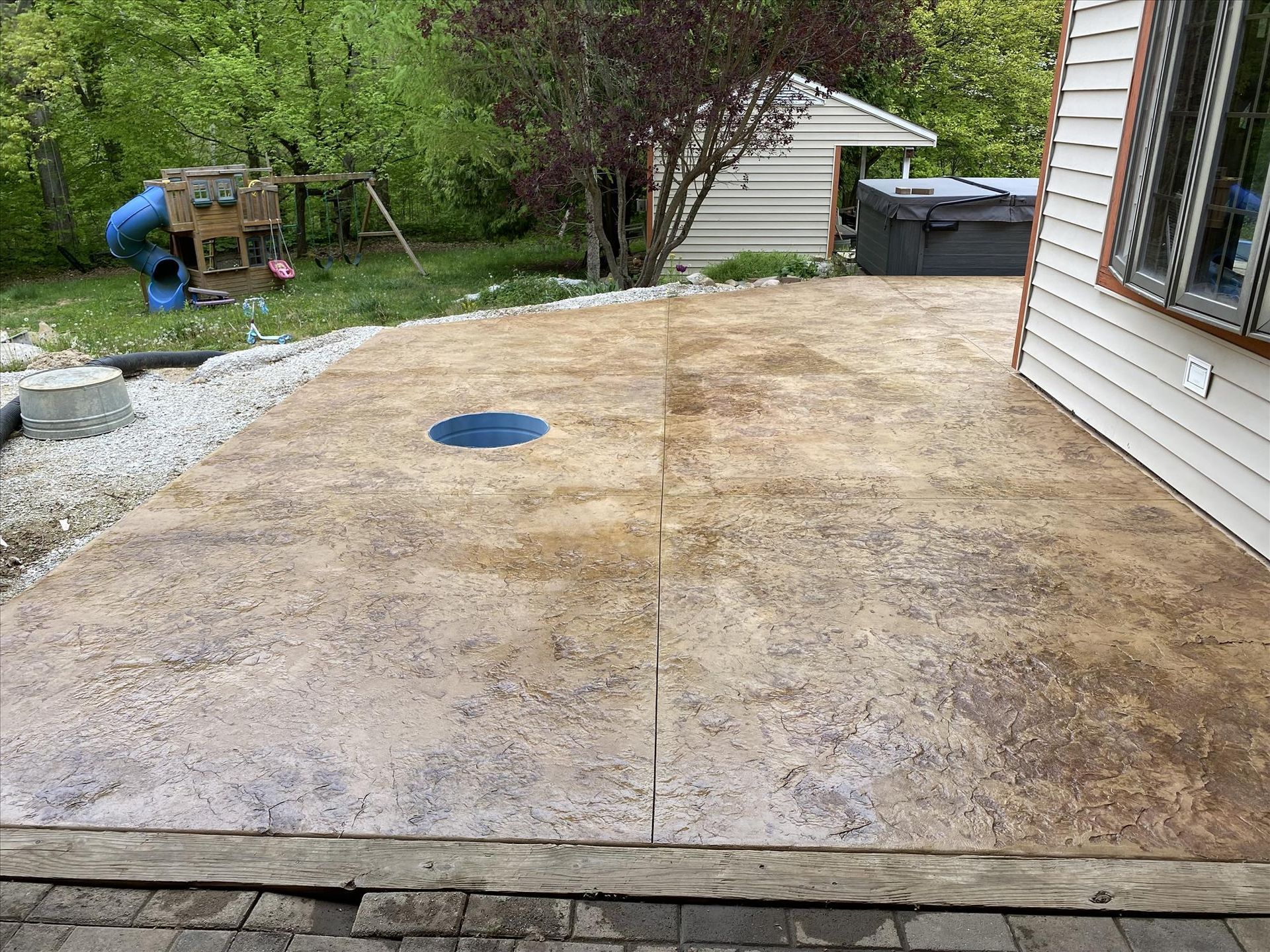 A concrete patio with a hole in the middle of it in front of a house.