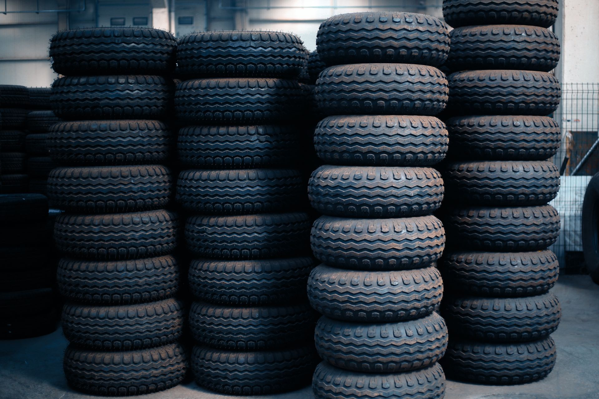 Stacks of black tires piled in rows in a warehouse or storage yard
