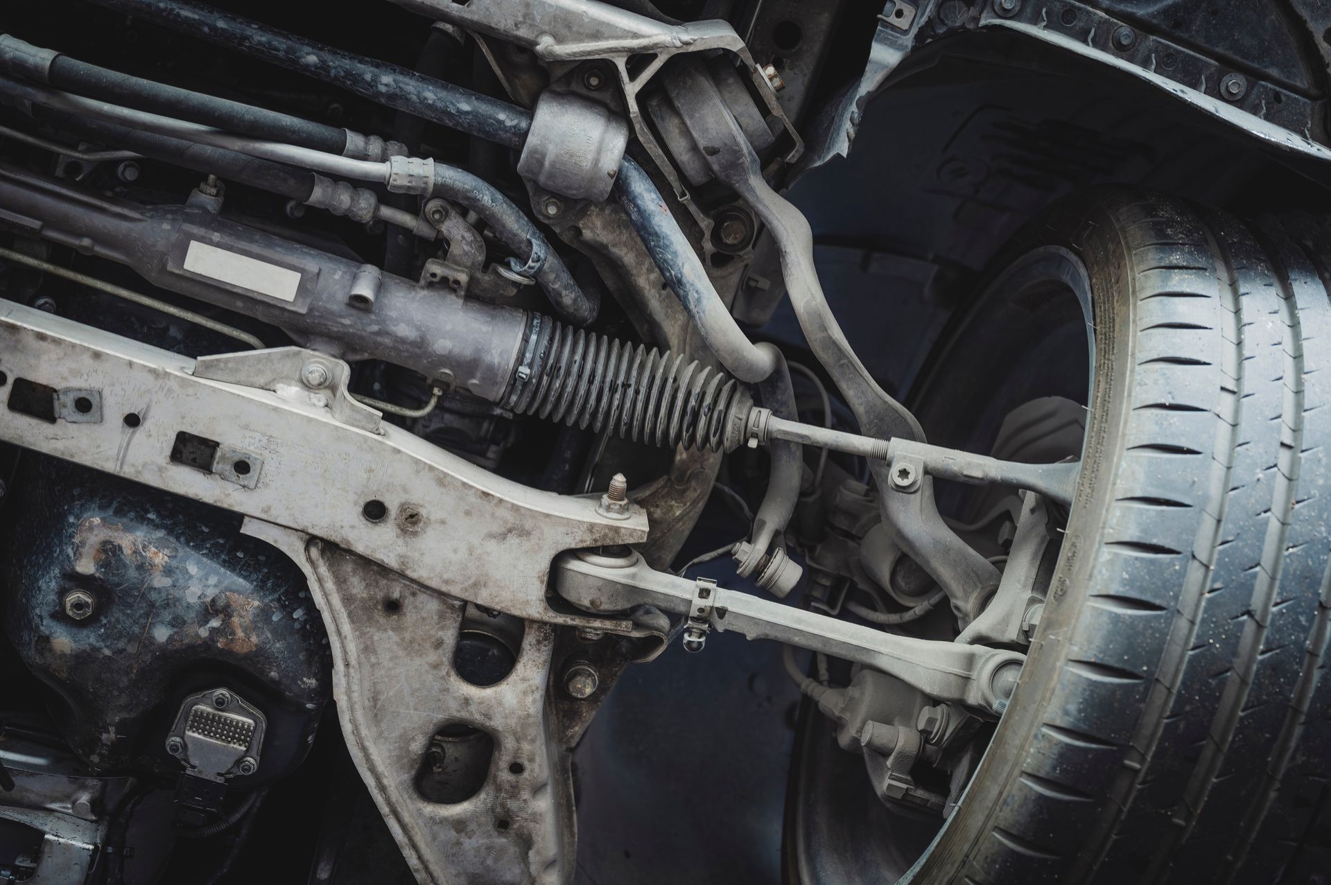 Damaged car suspension and wheel assembly with exposed components and debris underneath