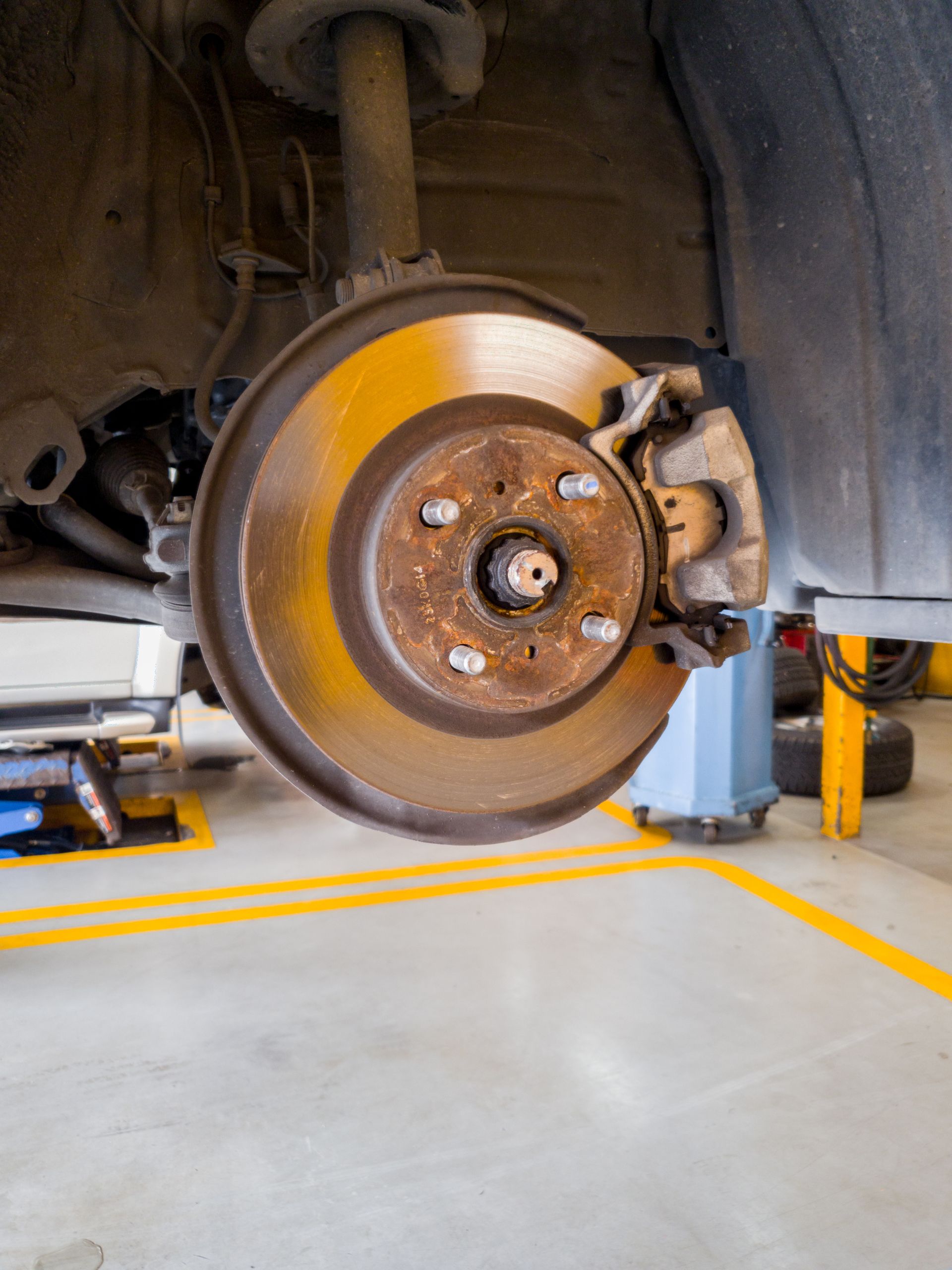 Car wheel and brake rotor in a garage, with the vehicle lifted on a jack