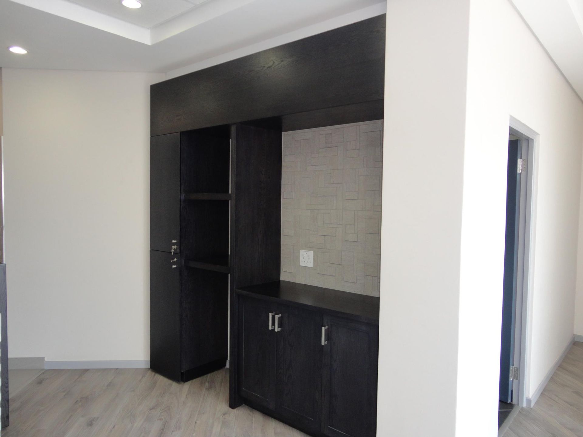 An Empty Room With Black Cabinets and a White Wall — Nyon Shopfitters in Morisset, NSW
