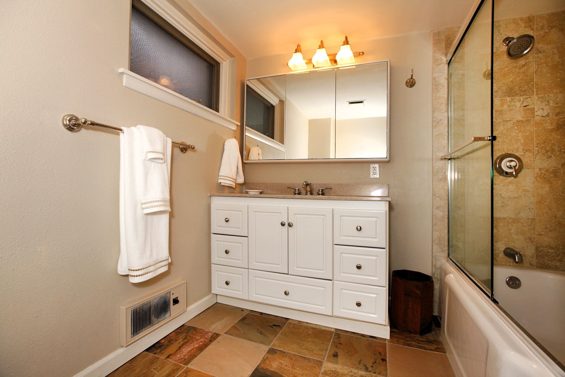 Modern basement bathroom with white vanity, glass shower, and tile flooring