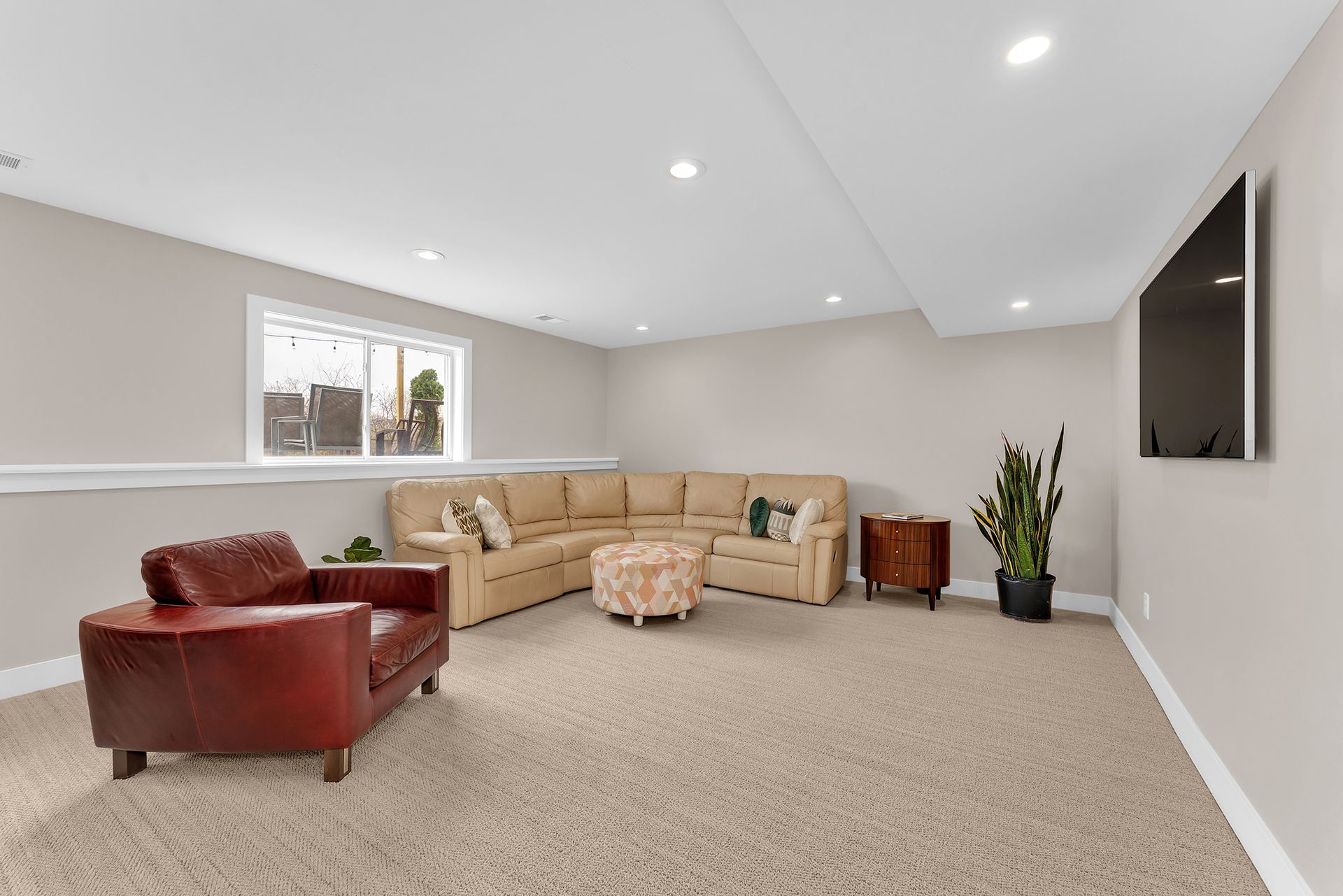 A living room with a couch , chair , ottoman and television.