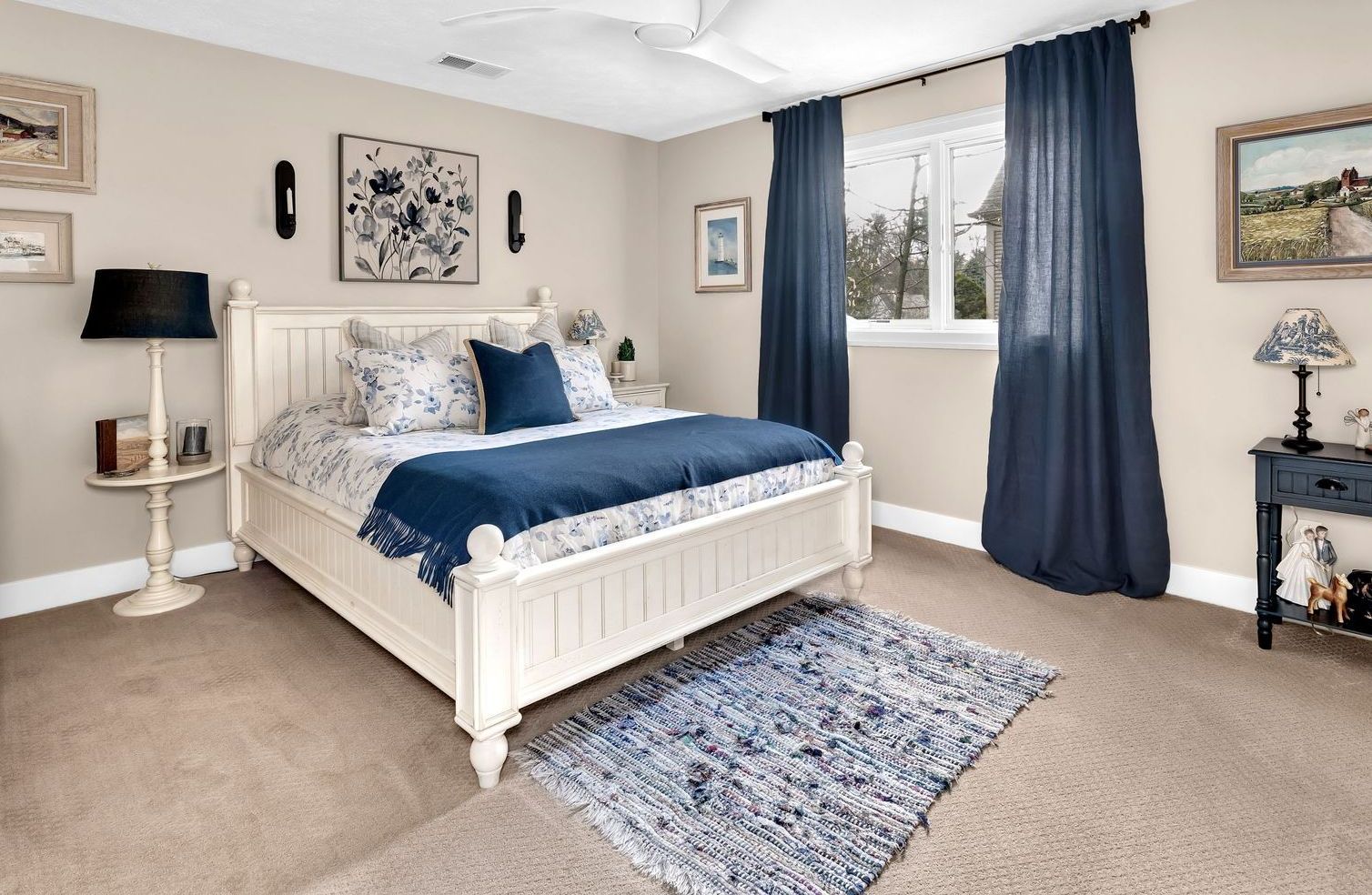 A bedroom with a white bed and blue curtains.