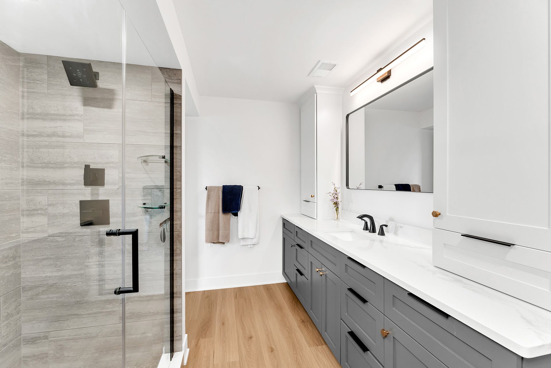 A bathroom with two sinks , a walk in shower and a large mirror.