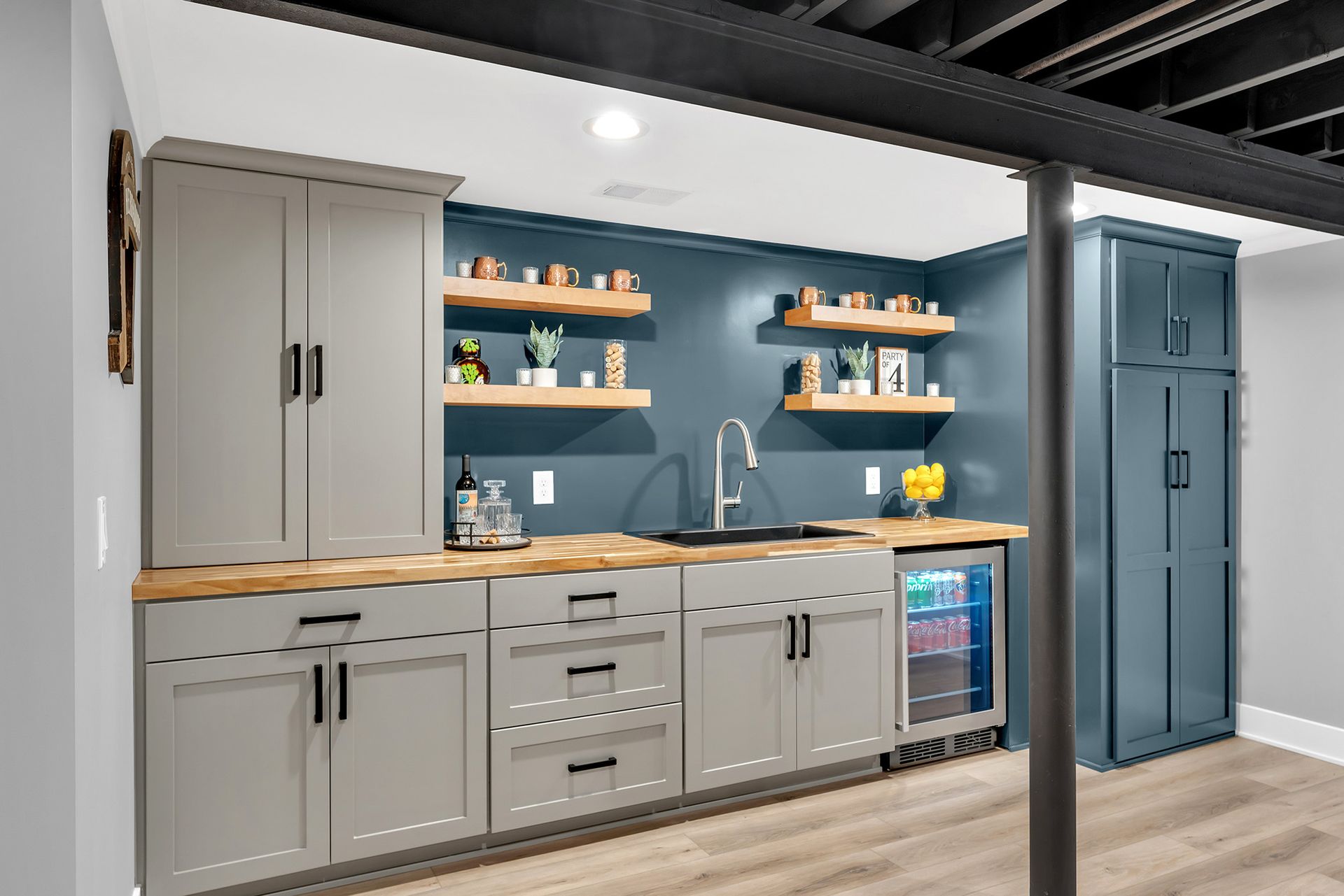 A wet bar with a sink , cabinets , shelves and a refrigerator.