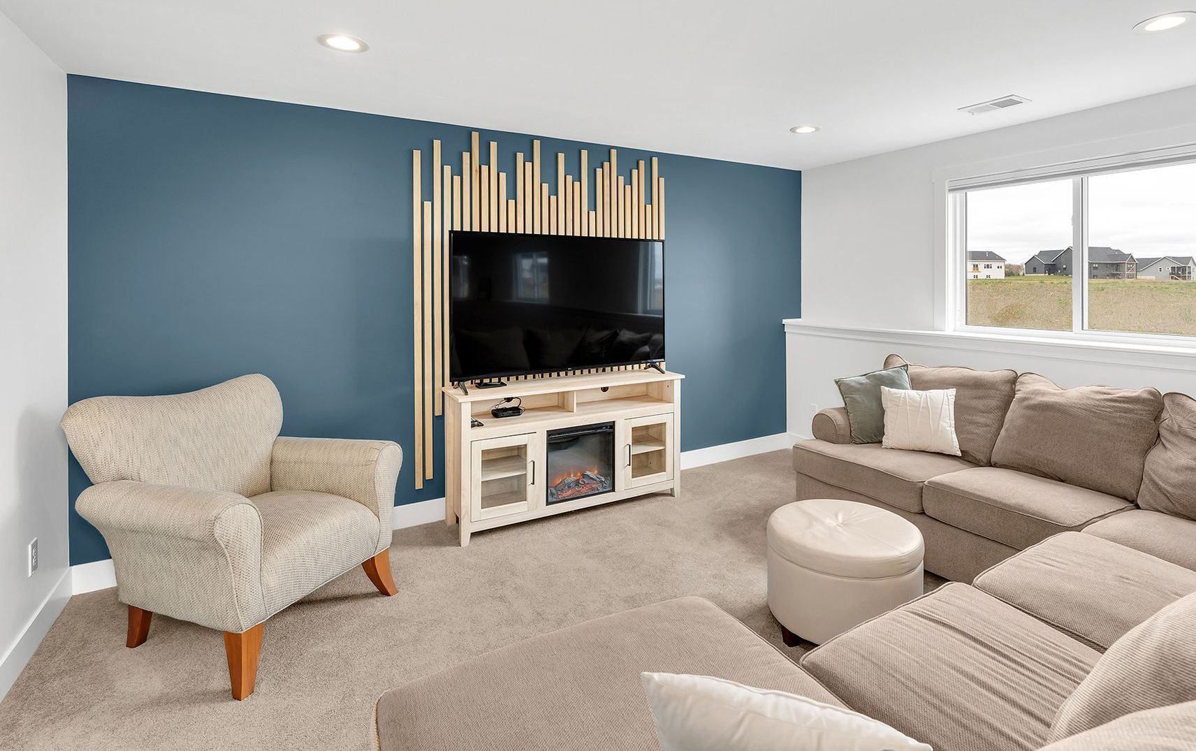 A living room with a couch , chair , television and fireplace.