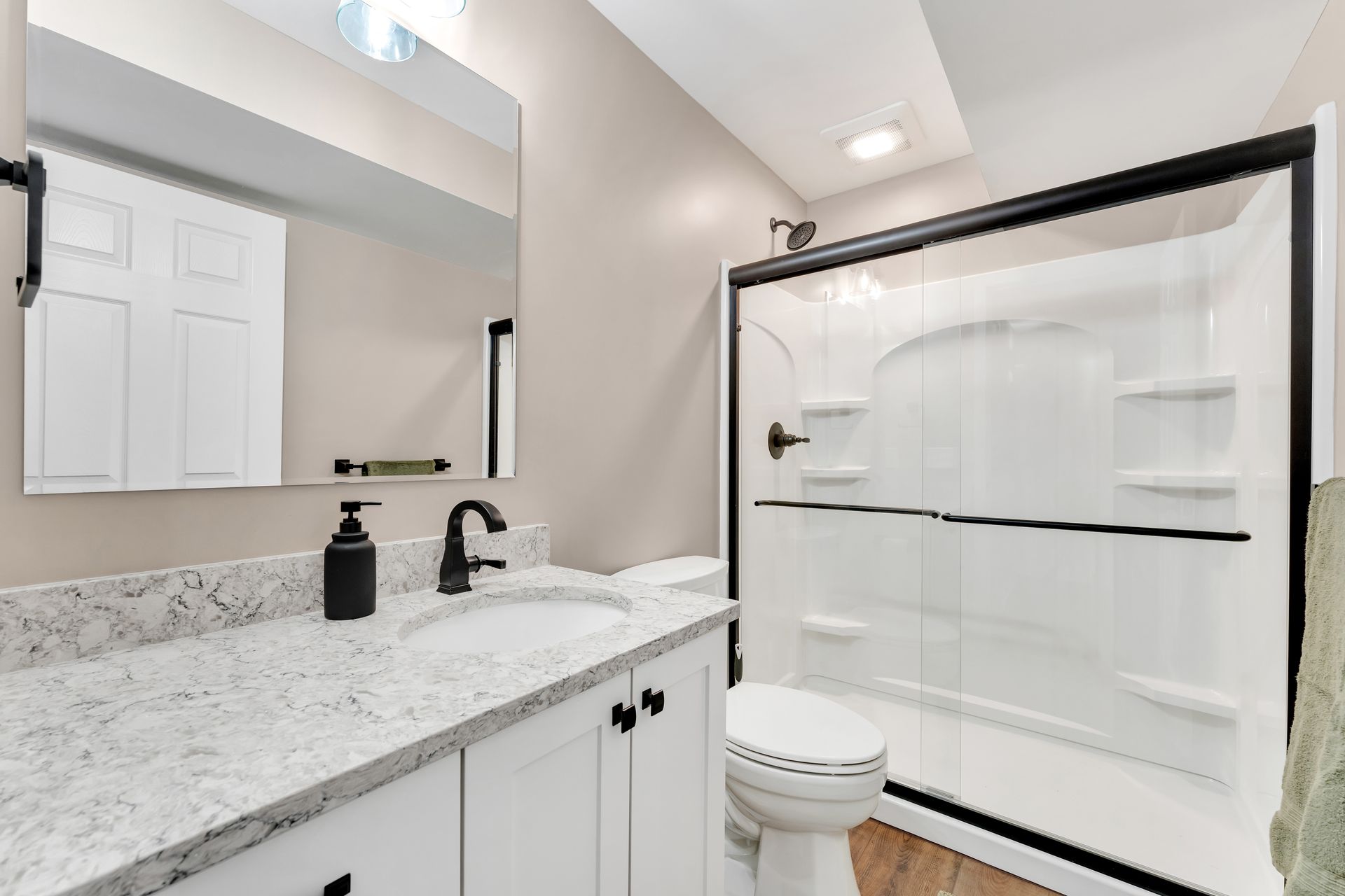 A bathroom with a sink , toilet , shower and mirror.