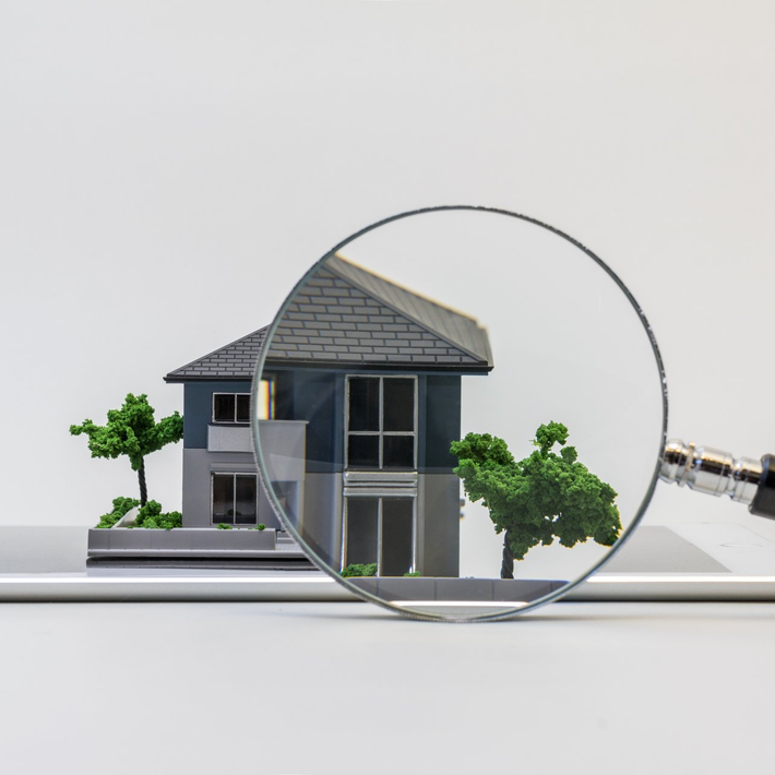magnifying glass pointing in a model house