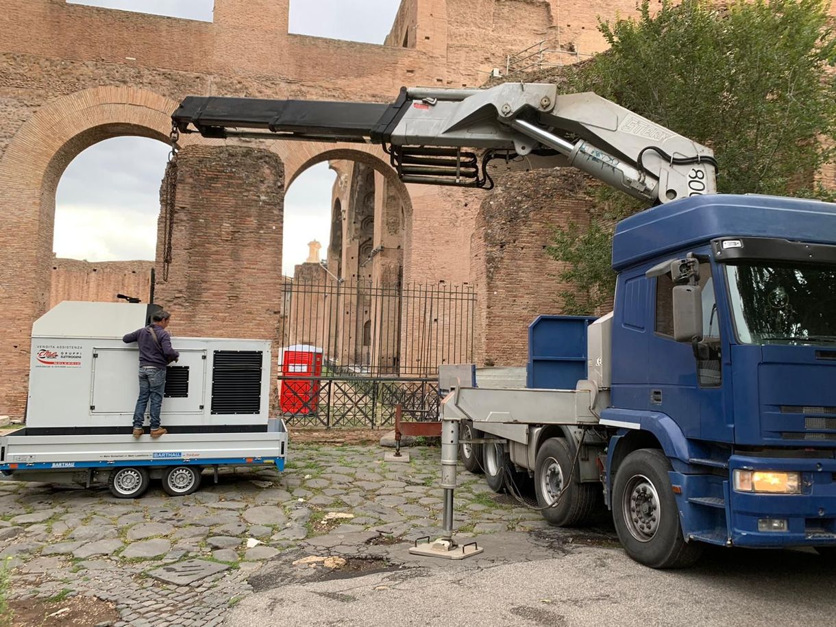 Sezione di sollevamento sollevata da una gru montata su un camion a pianale in un'area industriale.