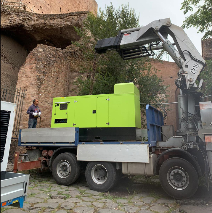 Sezione di sollevamento sollevata da una gru montata su un camion a pianale in un'area industriale.