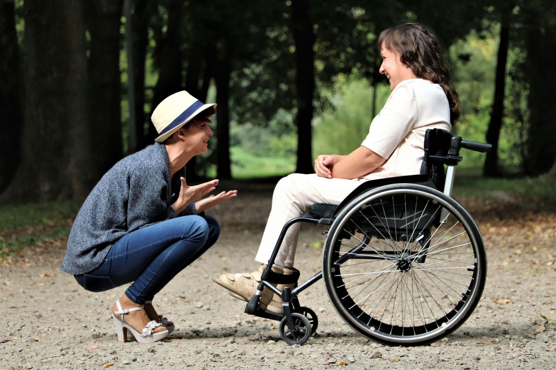 Woman in wheelchair talking with another woman in outdoor park.
