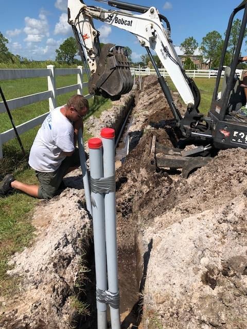 a man is kneeling in the dirt next to a bobcat excavator .