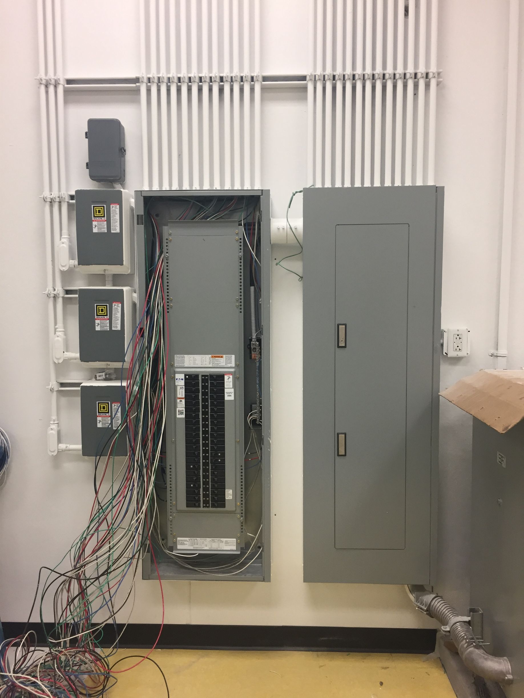 a room with a lot of wires hanging on the wall and a electrical box .