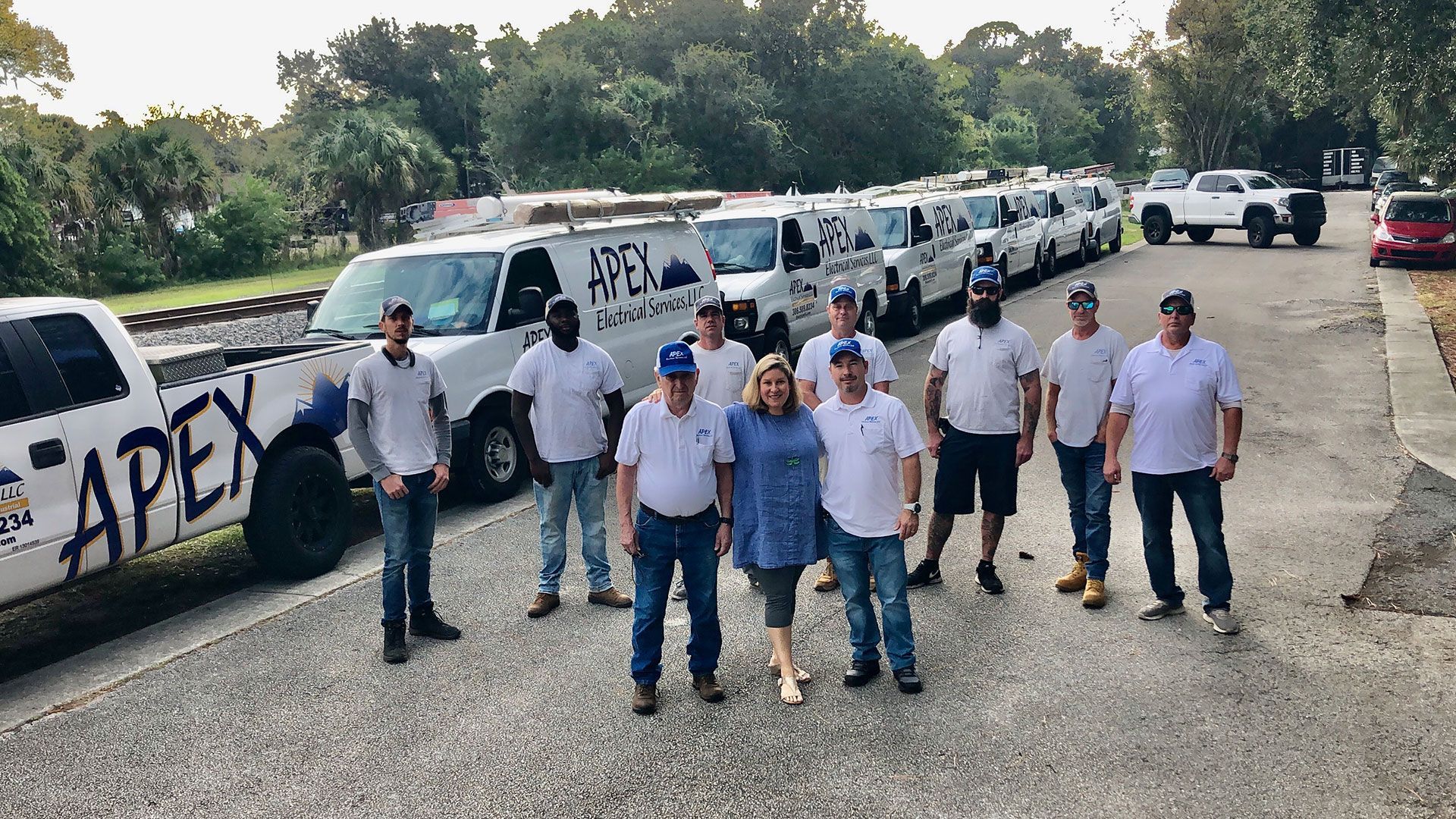 a group of people standing in front of a row of apex vans