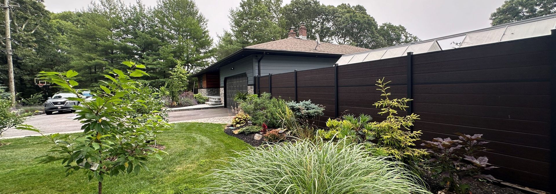 A black fence is surrounding a house in a backyard.