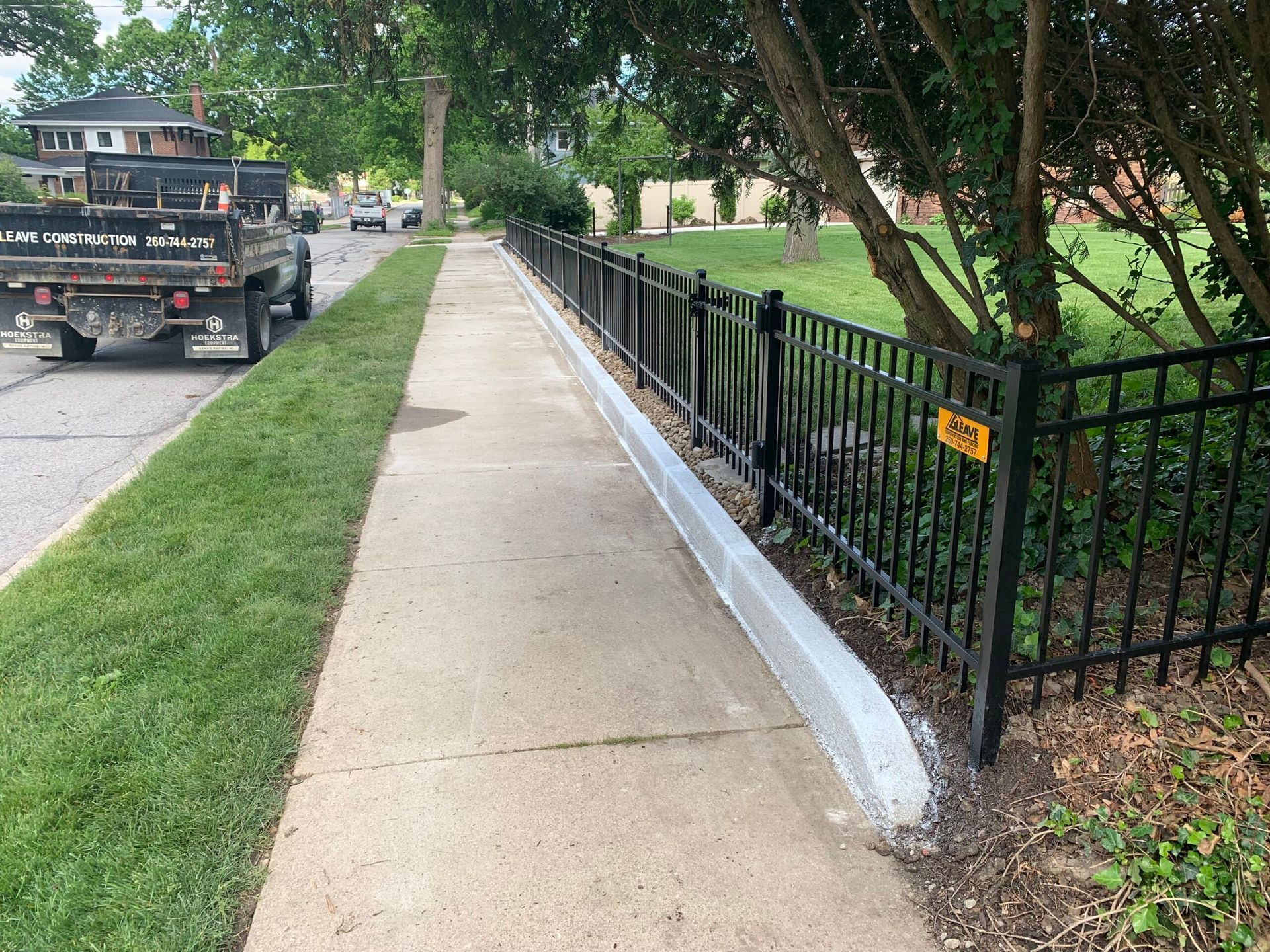 A truck is parked on the side of the road next to a fence.