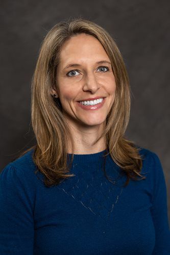 Smiling woman in a blue sweater against a dark studio background