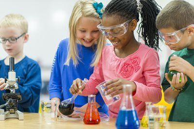 Children doing science experiments with colorful liquids in a classroom lab