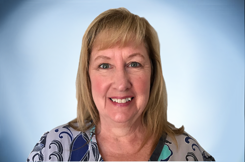 Smiling woman in a patterned blouse against a light blue background