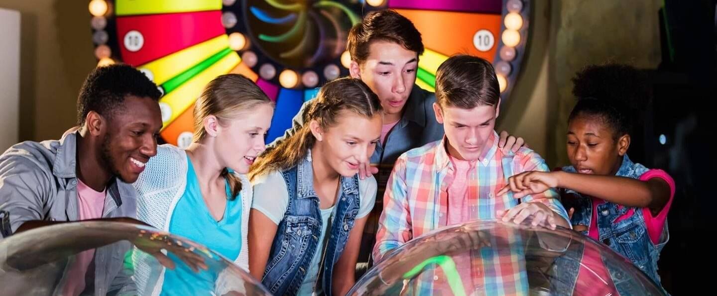 Friends gathered around a glowing interactive exhibit, smiling and pointing at colorful lights