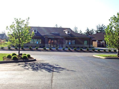 Single-story brick building with a dark roof and landscaped parking lot in front